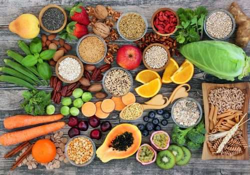 alimentos dispuestos sobre una mesa con frutas, semillas, frutos secos y frescos, muchos colores